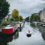 A serene view of houseboats and a small boat on an Amsterdam canal.