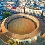 Breathtaking aerial view of the historic Plaza de Toros in Ronda, Spain, bathed in sunlight.