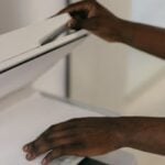 Hands adjusting document on a scanner in an office environment.