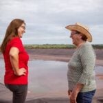 Two women engaging in conversation at a scenic rural orange farm in Brazil.