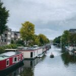 A picturesque Amsterdam canal lined with boat houses and a small boat navigating the water.