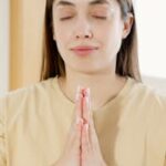 Calm woman practicing meditation indoors with eyes closed, exuding peacefulness.