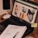 Laptop displaying pregnancy photos on desk with notepad and smartphone setup.
