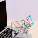 Mini shopping cart on a laptop symbolizes online shopping and e-commerce themes.