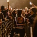 Security guard monitoring a lively concert crowd with smart phones at night.