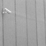 Two surveillance cameras mounted on a textured metal wall exhibiting modern architecture.